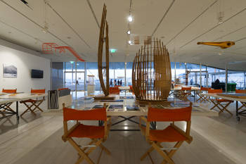 Photo showing an interior space in which there are some square tables on which there are pictures and memos